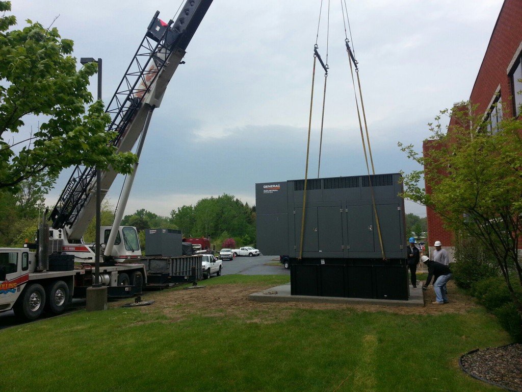 Crane lifting Generac standby generator off concrete pad during removal